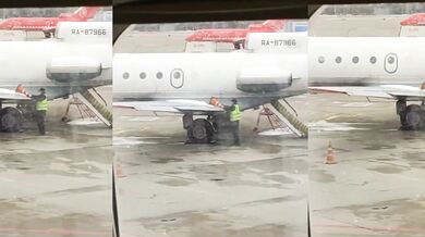 Zaměstnanec letiště používá dopravní kužel k odstranění ledu z letadla